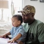 A father and child share a precious moment coloring together indoors, highlighting family bonds and closeness.