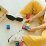 A young child playing creatively with colorful wooden blocks indoors, fostering learning and development.