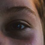 A close-up portrait of a child's eye, capturing subtle expressions and natural light details.