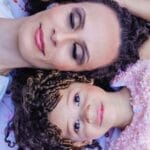 A heartwarming image of a mother and daughter lying together, smiling and bonding.