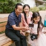 Asian family bonding while exploring photography in a park. Capturing joyful moments together.