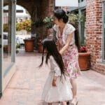 A mother and daughter window shopping in a charming urban brick-lined walkway.