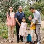 A joyful Asian family enjoys a day outdoors in a lush garden, promoting inclusion and togetherness.