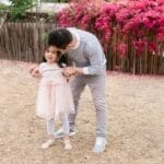 A father shares a joyful moment with his daughter in a blooming garden with vibrant flowers.