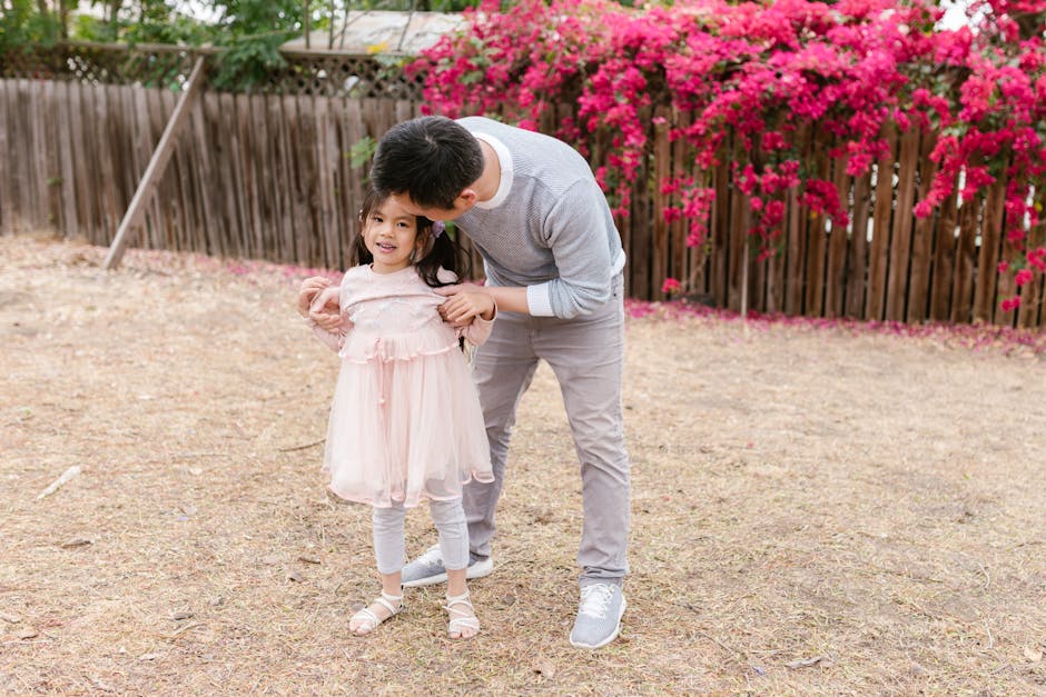 A father shares a joyful moment with his daughter in a blooming garden with vibrant flowers.