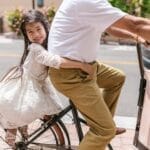 Young girl with long hair enjoys a bicycle ride on a sunny day outdoors.