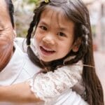 Happy girl enjoying a fun piggyback ride with her grandparent in an outdoor setting.