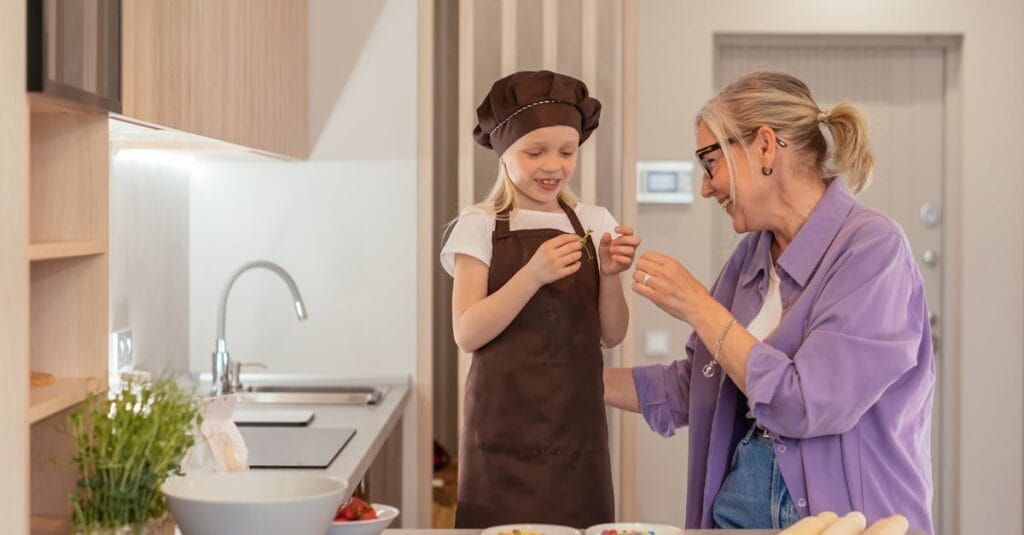 A joyful moment of a grandmother and granddaughter baking sweets in a modern kitchen.