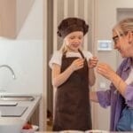 A joyful moment of a grandmother and granddaughter baking sweets in a modern kitchen.