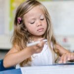 A young girl attentively writing in a classroom, capturing a moment of focused learning.