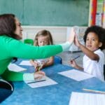 A teacher and students enjoying a high five during a classroom learning activity.