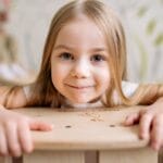 Close-up of a happy young girl smiling, showcasing innocence and joy in a bright setting.