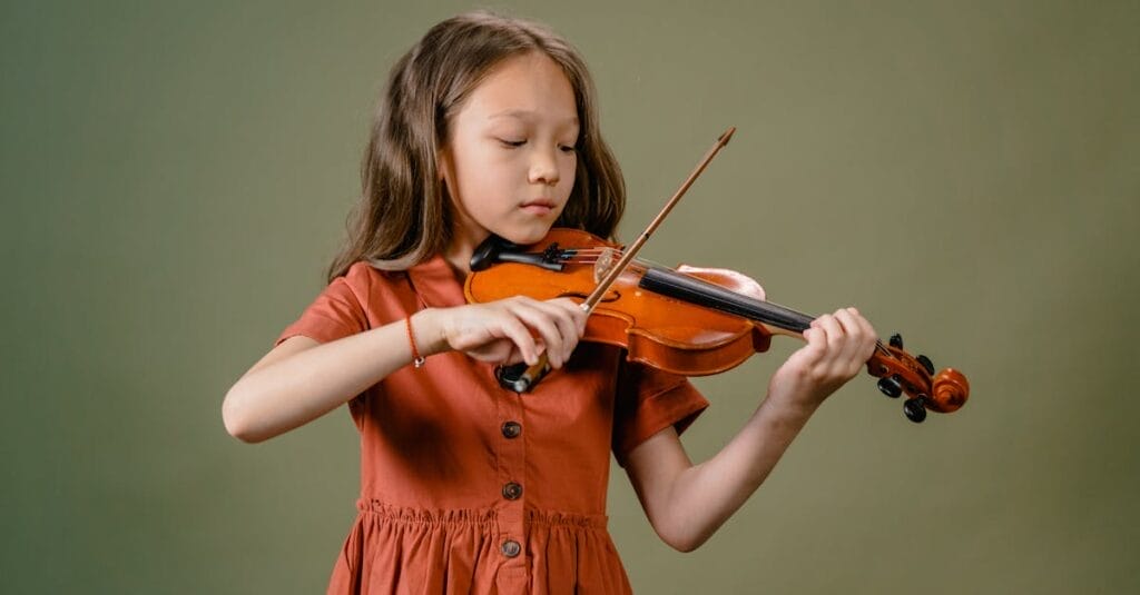 A young girl playing a violin with focus and concentration in a studio setup.