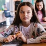 Two students attentively participate in a classroom environment, showcasing a back-to-school theme.