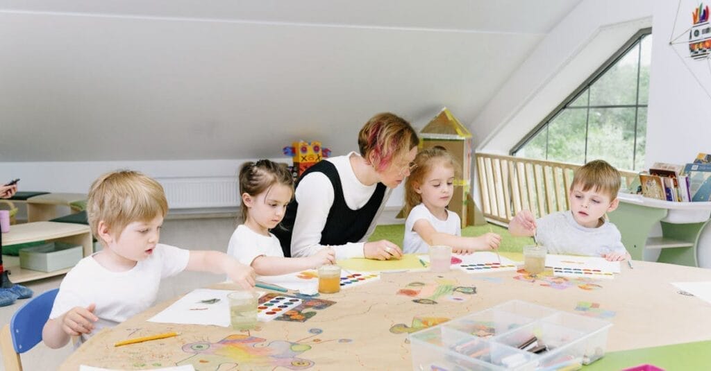 Young children engaging in art activities with a teacher in a bright kindergarten classroom.