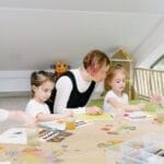 Young children engaging in art activities with a teacher in a bright kindergarten classroom.