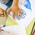 Children painting with watercolors and colored pencils, fostering creativity and learning in a fun environment.