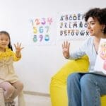 Teacher and child engage in counting and learning activities in a preschool classroom.