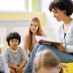 Teacher reading to preschool kids in a colorful classroom setting.