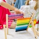 Children actively learning with a colorful abacus in a preschool setting, enhancing educational fun.