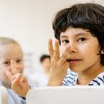 Children engaged in counting activity indoors with focus on learning and happiness.