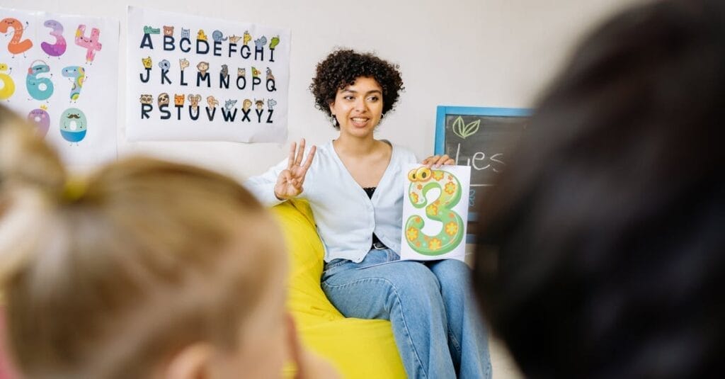 A teacher engages young students in a colorful classroom, promoting learning and diversity.