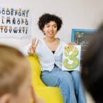 A teacher engages young students in a colorful classroom, promoting learning and diversity.