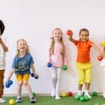 Happy diverse children playing with colorful balls indoors, showcasing fun and friendship.