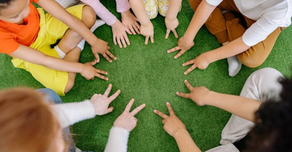 Children sitting in a circle playing fun team games on artificial grass.