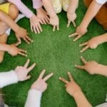 Children sitting in a circle playing fun team games on artificial grass.