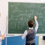 Teacher and student engage in a geometry lesson, solving problems on the chalkboard.