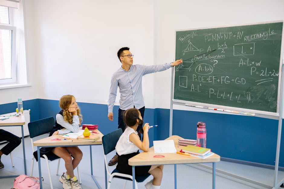 Teacher pointing at chalkboard with students in classroom learning geometry.