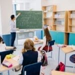 Children in a classroom focused on a math lesson with a teacher. Bright and educational atmosphere.