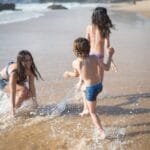 A family enjoys a sunny day on a Portuguese beach, splashing in the waves.