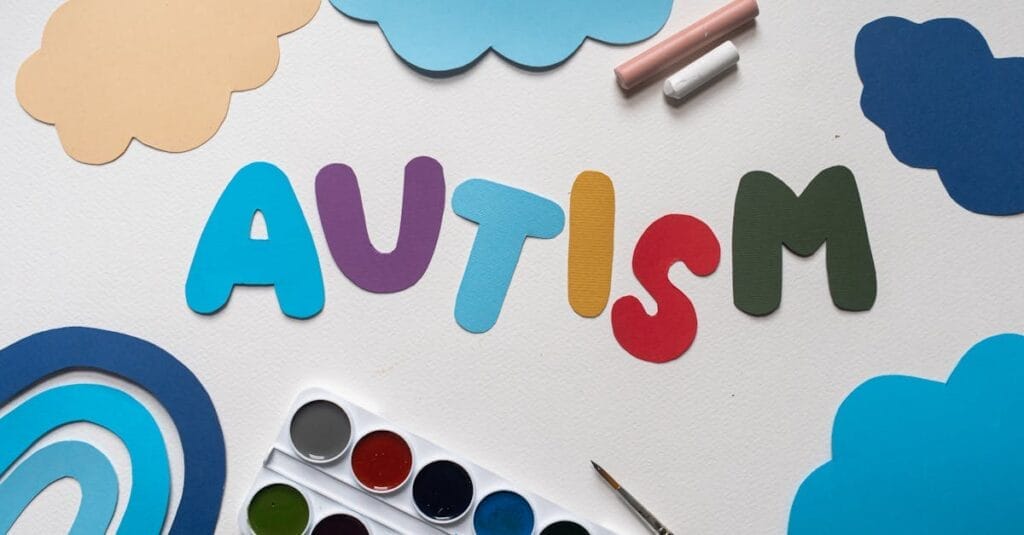 A vibrant autism awareness theme with watercolor paints and cutouts, featuring the word 'Autism'.