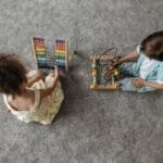 Two children enjoy educational play with a colorful abacus and wooden toy.