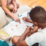 A child receives tutoring assistance with homework, highlighting education and learning.