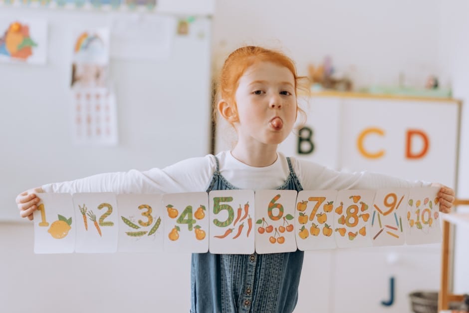 Happy redhead child holding number cards in a classroom, enjoying fun learning.
