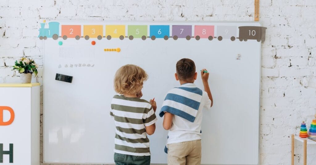 Two boys writing on a colorful classroom whiteboard, enhancing learning.