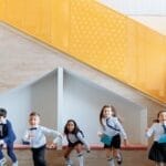 Group of cheerful children playing indoors near a colorful staircase, enjoying their school day.