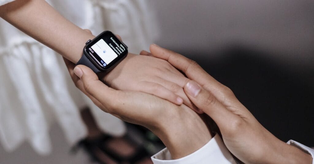 A close-up of an adult holding a child's hand wearing a smartwatch, showcasing technology and care.