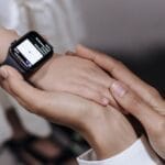 A close-up of an adult holding a child's hand wearing a smartwatch, showcasing technology and care.