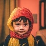 Charming portrait of a little boy in a colorful traditional scarf indoors. Perfect for themed visuals.