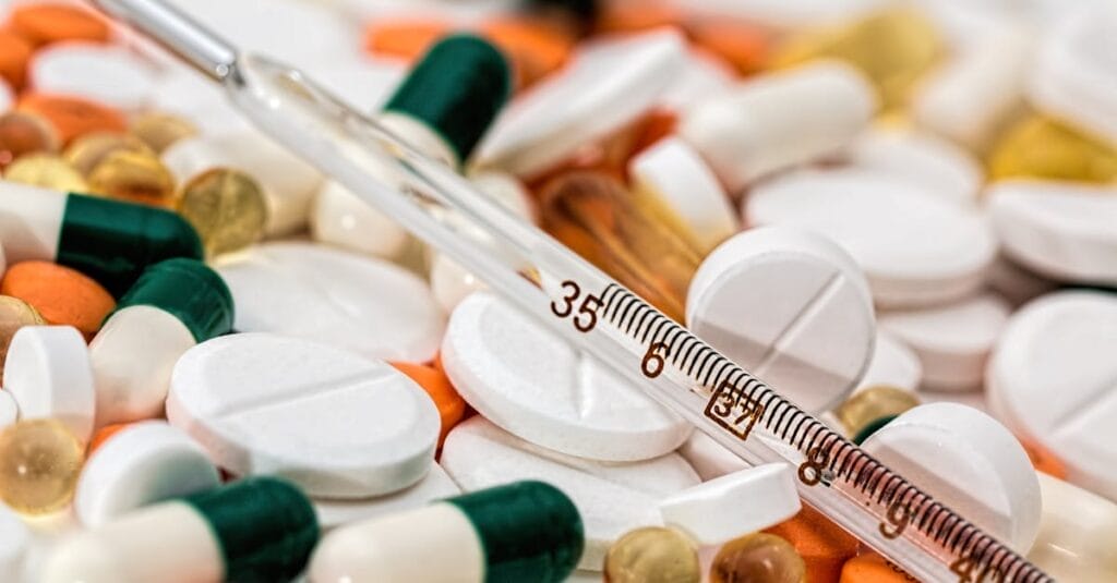 Close-up image showing various pills and a thermometer, emphasizing health and medicine.