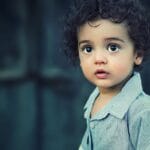 Charming portrait of a young boy with curly hair and striking eyes.