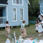 Children enjoying a sack race with parents cheering in a backyard garden.