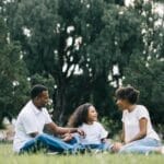 A happy black family enjoying quality time together outdoors in a lush green park.