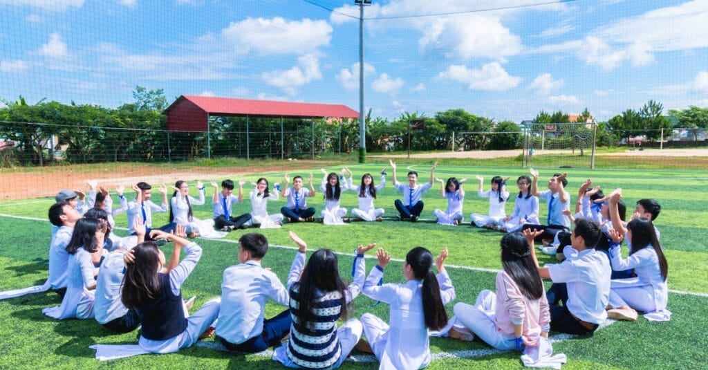 Students seated in a circle on a school field engaging in outdoor activities.