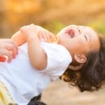 A happy baby enjoying playful moments outdoors, captured in warm summer lighting.