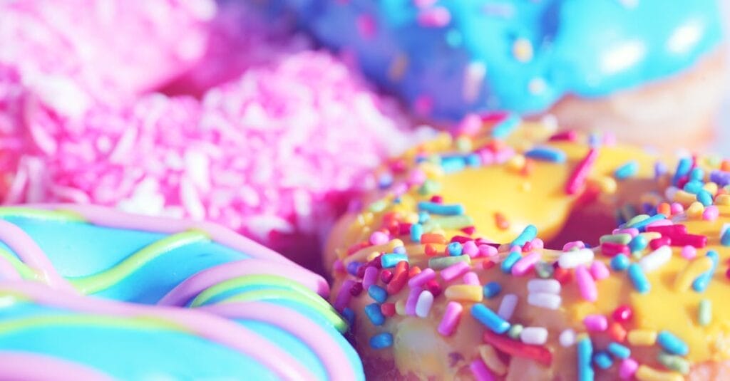 Close-up of assorted donuts with colorful icing and sprinkles, showcasing sweet indulgence.